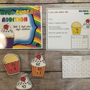 May include: Colorful cupcake addition game for kids. The game includes a set of cupcake-shaped cards with addition problems and a separate answer key card. The cards feature colorful cupcakes with sprinkles and cherries.