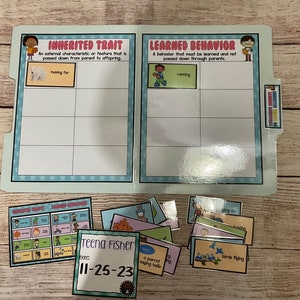 May include: A blue and white folder with the words "Inherited Trait" and "Learned Behavior" on it. The folder is divided into two sections, each with a definition and examples. There are also several cards with images and words on them, such as "having fur", "running", and "birds flying".