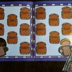 May include: A colorful educational book with multiplication problems. Each page features illustrations of bread slices with multiplication equations like "5x4" and "5x7". The book has a purple border and includes cartoon characters.