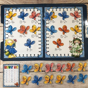 May include: A blue folder with a colorful butterfly theme. The folder has math problems with butterflies and numbers. An answer key is included with a grid of letters and numbers. There are also colorful butterfly cutouts with numbers on them.