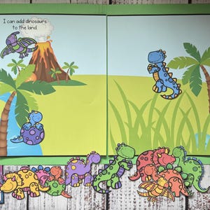 May include: A green folder with a dinosaur theme. The folder has a landscape scene with a volcano, palm trees, and dinosaurs. The text "I can add dinosaurs to the land" is visible. A collection of dinosaur cutouts are at the bottom.
