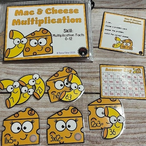 May include: A set of colorful, illustrated, educational game pieces for learning multiplication facts. The pieces feature a cartoon macaroni and cheese theme with the text "Mac & Cheese Multiplication" and "Skill: Multiplication Facts 0-12".