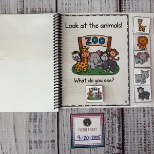 May include: An educational spiral-bound book with the text "Look at the animals!" and "What do you see?" features cartoon animals and matching picture cards. A small card with the text "ZOO" is also included. A card with the name "Teena Fisher" and the date "9-20-2025" is also present.