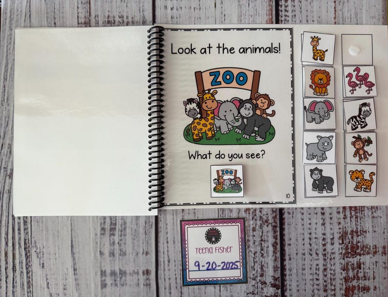 May include: An educational spiral-bound book with the text "Look at the animals!" and "What do you see?" features cartoon animals and matching picture cards. A small card with the text "ZOO" is also included. A card with the name "Teena Fisher" and the date "9-20-2025" is also present.