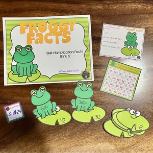 May include: Educational math game with a frog theme. The set includes cards with multiplication problems, an answer key, and cards with the text "FROGGY FACTS". The illustrations feature green frogs on lily pads.