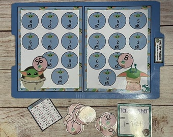 Könnte beinhalten: Ein blauer Ordner mit einem Multiplikationsspiel mit Bildern von Baby Yoda. Das Spiel enthält eine Reihe von Kreisen mit Zahlen und Multiplikationsaufgaben. Der Ordner enthält auch eine Reihe von Zählern mit Zahlen darauf. Der Text auf dem Ordner lautet "Space Baby Problems" und "Shop for Humpicotian".