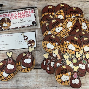 May include: A set of 24  chicken leg and waffle shaped cards with CVC words printed on them. The cards are designed for a short vowel CVC match game. The cards are in a clear plastic zippered pouch. The text on the pouch reads "Chicken & Waffle CVC Match".