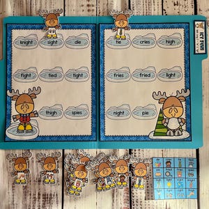 May include: A blue folder with a moose theme. The folder has two sides, each with a set of words. The words are: knight, sight, die, tie, cries, high, fight, tied, tight, fries, fried, light, thigh, spies, night, pie. There are also several moose stickers on the folder.