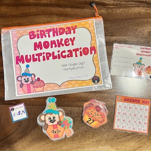 May include: A clear plastic bag filled with educational materials for learning single-digit multiplication. The bag contains a title card that says "Birthday Monkey Multiplication", a set of colorful cards with multiplication problems and answers, and a monkey-themed answer key.