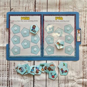 May include: A blue and white educational game with the words "PUSH" and "PULL" on the front. The game has two sides, one for push and one for pull. Each side has a set of blue and white hexagon shapes with white dots in the center. There are also pictures of people pushing and pulling objects.