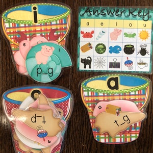 Pu&ograve; includere: Un set di quattro secchielli di plastica colorati con lettere e immagini all'interno. I secchielli sono decorati con motivi a scacchi rossi e bianchi. Le lettere sono "i", "a", "d", e "t". Le immagini includono un maiale, un granchio, una conchiglia e un pesce. I secchielli fanno parte di un gioco di apprendimento per bambini. La chiave di risposta &egrave; anche inclusa, mostrando la lettera corretta per ogni immagine.