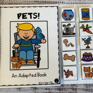 May include: An adapted book titled "PETS!" with a spiral binding. The cover features a cartoon illustration of a person holding a blue bird, with a cat at their feet. Additional illustrated tiles of pets and pet supplies are included.