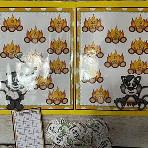May include: A printable educational activity for kids featuring a yellow folder with a campfire theme. The folder has a variety of addition problems with a skunk character and marshmallows. The answer key is visible on the bottom left corner of the image.