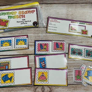 May include: A clear plastic pouch containing a "Summer Stamp Match" game with colorful illustrations of crabs, suns, surfboards, sunglasses, and other summer-themed images. The game includes matching cards and instructions.