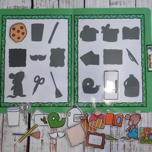 May include: A green file folder featuring a shadow matching activity with various shapes and silhouettes. Below the folder are loose, colorful cutouts of objects including a mouse, scissors, a milk jug, a book, and a cookie, designed for placement.