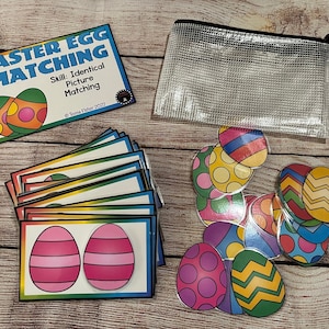 May include: Easter Egg Matching game with colorful eggs with different patterns. The game includes 10 cards with two eggs each and 10 individual eggs. The cards are rainbow colored and the eggs are printed on white cardstock. The game comes in a clear plastic zippered bag.