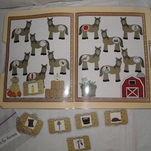 May include: Educational game featuring a file folder with illustrations of horses, each with a different object inside. Includes matching cards with objects like a spool of thread and a lamp. Text on the file folder reads "Hay is for Horses!"
