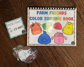 Pode incluir: Um livro colorido intitulado "Farm Friends Color Sorting Book" com uma encadernação em espiral preto e branco. O livro tem imagens de animais de fazenda com rostos de diferentes cores. Há um conjunto separado de rostos de animais de fazenda com diferentes cores.