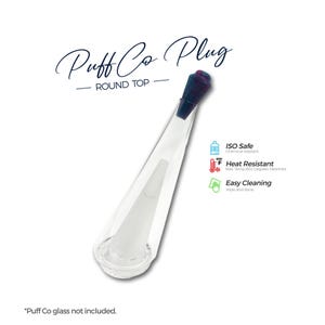 May include: A clear glass Puff Co Plug with a dark purple top. The plug is cone-shaped with a round base and features the text "Puff Co Plug - ROUND TOP". The image also includes icons indicating it is ISO safe, heat resistant, and easy to clean.
