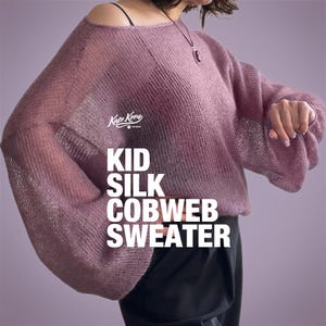 以下が含まれることがあります： モーヴ色のKid Silk Cobwebセーター。長くてフレアな袖が特徴です。オフショルダーのデザインは繊細でオープンな織り方です。「Kid Silk Cobweb Sweater」の文字が大きな白い大文字で表示されています。