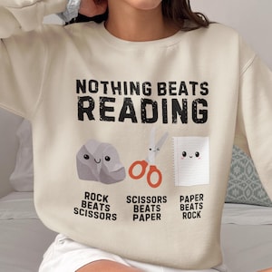 Felpa "Nothing Beats Reading", grazioso pullover per amanti dei libri con carta e forbici da sasso, regalo di lettura accogliente per insegnanti, bibliotecari e amanti dei libri