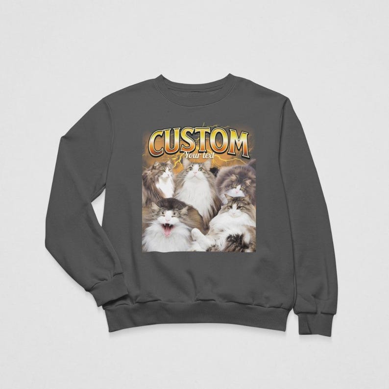 May include: A dark gray crewneck sweatshirt featuring a graphic print of five fluffy cats. Above the cats, the word CUSTOM is printed in large yellow letters, with the words Your text underneath. The background of the graphic features yellow lightning.