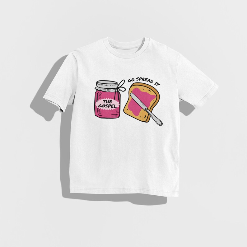 May include: White t-shirt featuring a cartoon illustration of a jar of jam labeled "THE GOSPEL" next to a slice of toast with jam and a knife. The text "GO SPREAD IT" is above the toast.