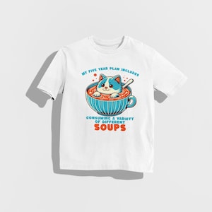 May include: White t-shirt featuring a cartoon cat in a bowl of soup. The text on the shirt reads "My five year plan includes consuming a variety of different soups."