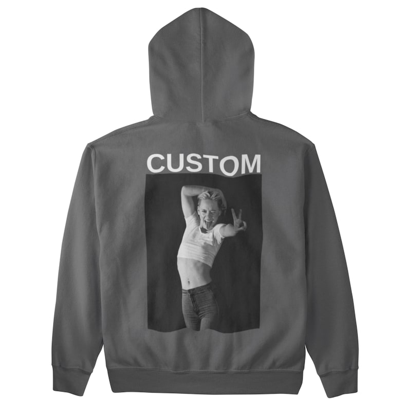 May include: A charcoal gray hoodie with a hood and a front pocket. The back features a black and white image of a person making a peace sign, with the word "CUSTOM" printed above the image.
