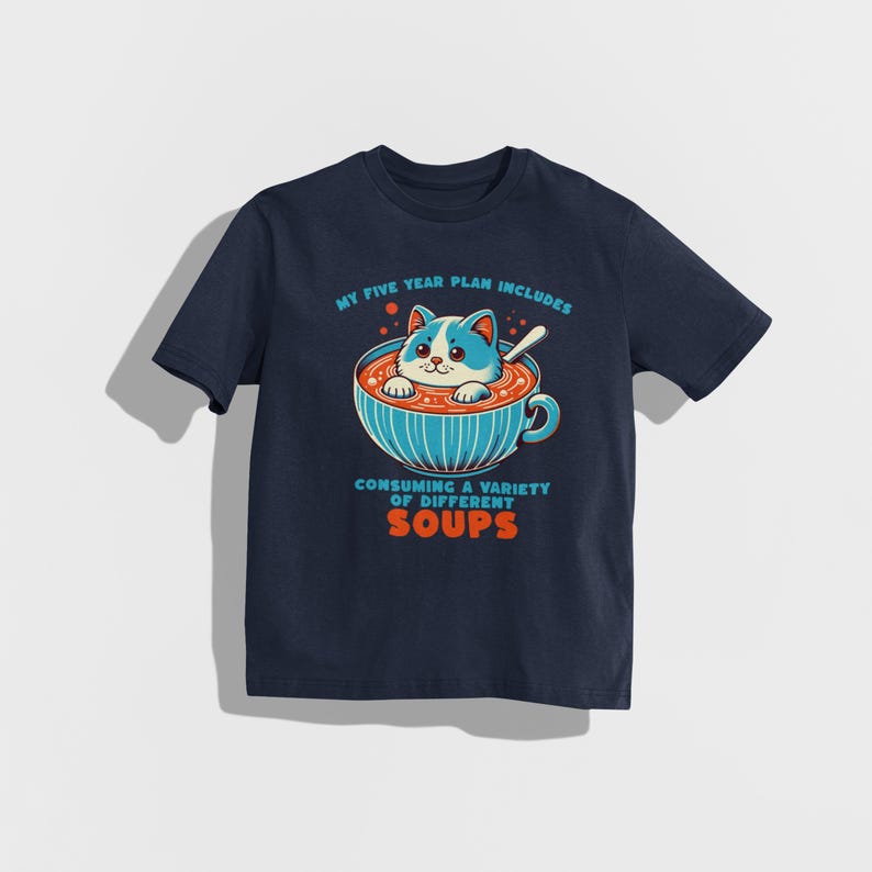May include: A navy blue t-shirt featuring a cartoon cat in a bowl of soup. The text on the shirt reads "My five year plan includes consuming a variety of different soups."