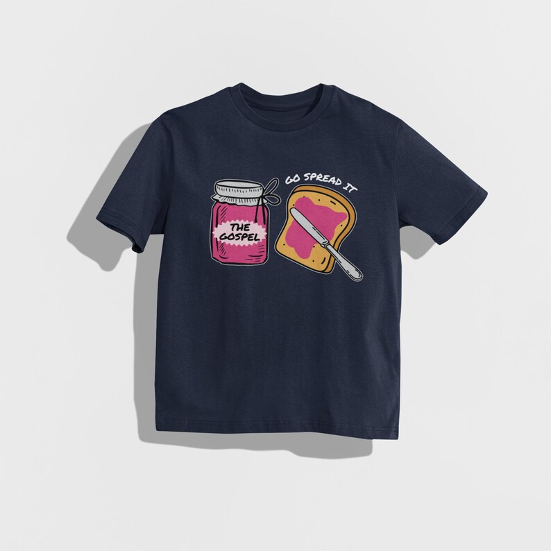 May include: Navy blue t-shirt featuring a graphic of a jar of jam labeled "The Gospel" and a slice of toast with jam and a knife. The text "Go Spread It" is above the toast. The design is in a cartoon style.