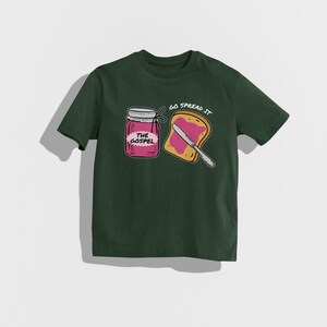 May include: Dark green t-shirt featuring a graphic of a jar labeled "THE GOSPEL" and a slice of toast with a knife, with the text "GO SPREAD IT". The design is in white, pink, and yellow.