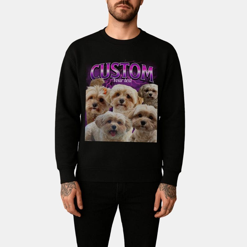 May include: A black crewneck sweatshirt featuring a graphic print of five small light-colored dogs. Above the dogs, the word CUSTOM is printed in large purple letters, with the words Your text printed in smaller white letters below it.
