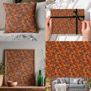 Op de afbeelding: Een vierkant sierkussen, een ingelijste print en een ingepakte geschenkdoos, allemaal met een herhalend bloemenpatroon in tinten oranje, bruin en grijs. De geschenkdoos is vastgebonden met een zwart lint. Thema: interieurdecoratie.