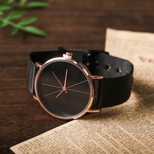 May include: A black and rose gold wristwatch with a black mesh band. The watch face is black with rose gold hands and markers.