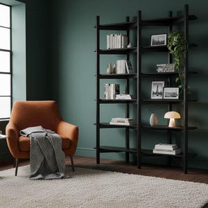 Lifestyle image of the black Wenge bookshelf in a moody, dark green room, styled with books and decor next to an orange armchair.