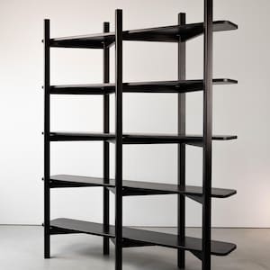 May include: A tall, black wooden bookshelf with five shelves. The shelves are supported by vertical posts and horizontal supports. The design is minimalist and modern, with a focus on clean lines and functionality. The bookshelf is freestanding.