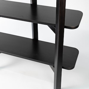 Close-up detail of the black Wenge bookshelf, showing the joint, legs, and rounded shelf corners.