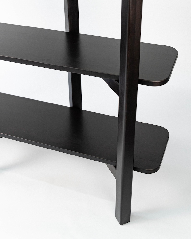 Close-up detail of the black Wenge bookshelf, showing the joint, legs, and rounded shelf corners.