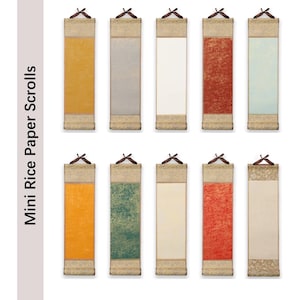 Könnte beinhalten: Eine Sammlung von zehn Miniatur-Reispapierrollen in verschiedenen Farben, darunter Gelb, Grau, Weiß, Rot und Grün. Jede Rolle hat eine dekorative Ober- und Unterseite mit einem hölzernen Aufhängemechanismus. Der Text "Mini Rice Paper Scrolls" ist sichtbar.