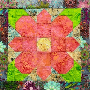 May include: A patchwork quilt block featuring a large pink flower with a yellow center. The flower is surrounded by green and brown squares. The quilt block is framed by a border of colorful floral fabric.