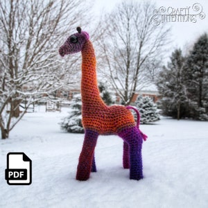 May include: A crocheted giraffe toy with a long neck and legs. The giraffe is made with orange, pink, and purple yarn. The toy is standing in the snow.