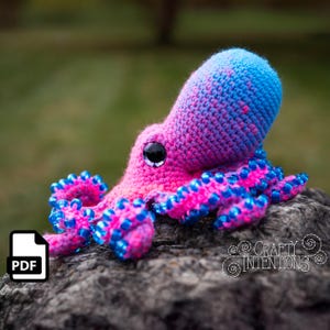 May include: A crocheted octopus amigurumi toy with pink and blue ombre yarn. The octopus has blue beads around its tentacles.