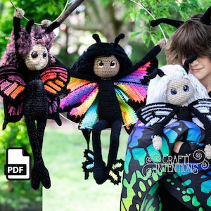 May include: Three crocheted butterfly dolls with colorful wings. The dolls are hanging from a metal ring. The dolls have different colored wings and faces. The dolls are made with black yarn. The dolls are hanging in front of a green background.