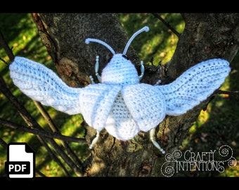 May include: A crocheted white butterfly with silver beads for accents. The butterfly is perched on a tree branch. The image includes the text "CRAFTY INTENTIONS" and a PDF icon.