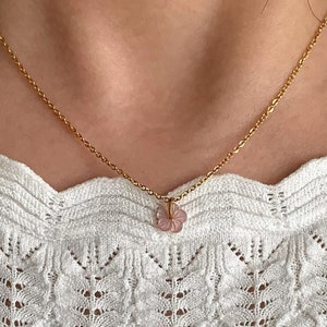 May include: A delicate gold chain necklace with a small pink flower pendant.
