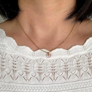 May include: A gold chain necklace with a small pink flower pendant.