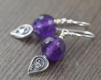 May include: A pair of silver earrings with purple amethyst gemstone beads and a silver teardrop charm.