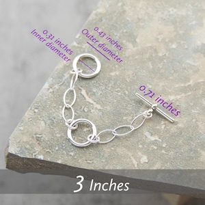 May include: Silver chain bracelet with a toggle clasp. The bracelet is 3 inches long and the clasp is 0.71 inches long. The inner diameter of the ring is 0.31 inches and the outer diameter is 0.43 inches.