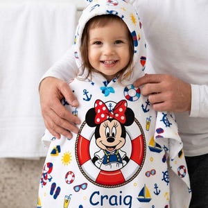 May include: White hooded toddler towel with a Minnie Mouse design in a life preserver. The towel features a nautical theme with anchors, sailboats, and the name "Craig". The hood has small bear ears.
